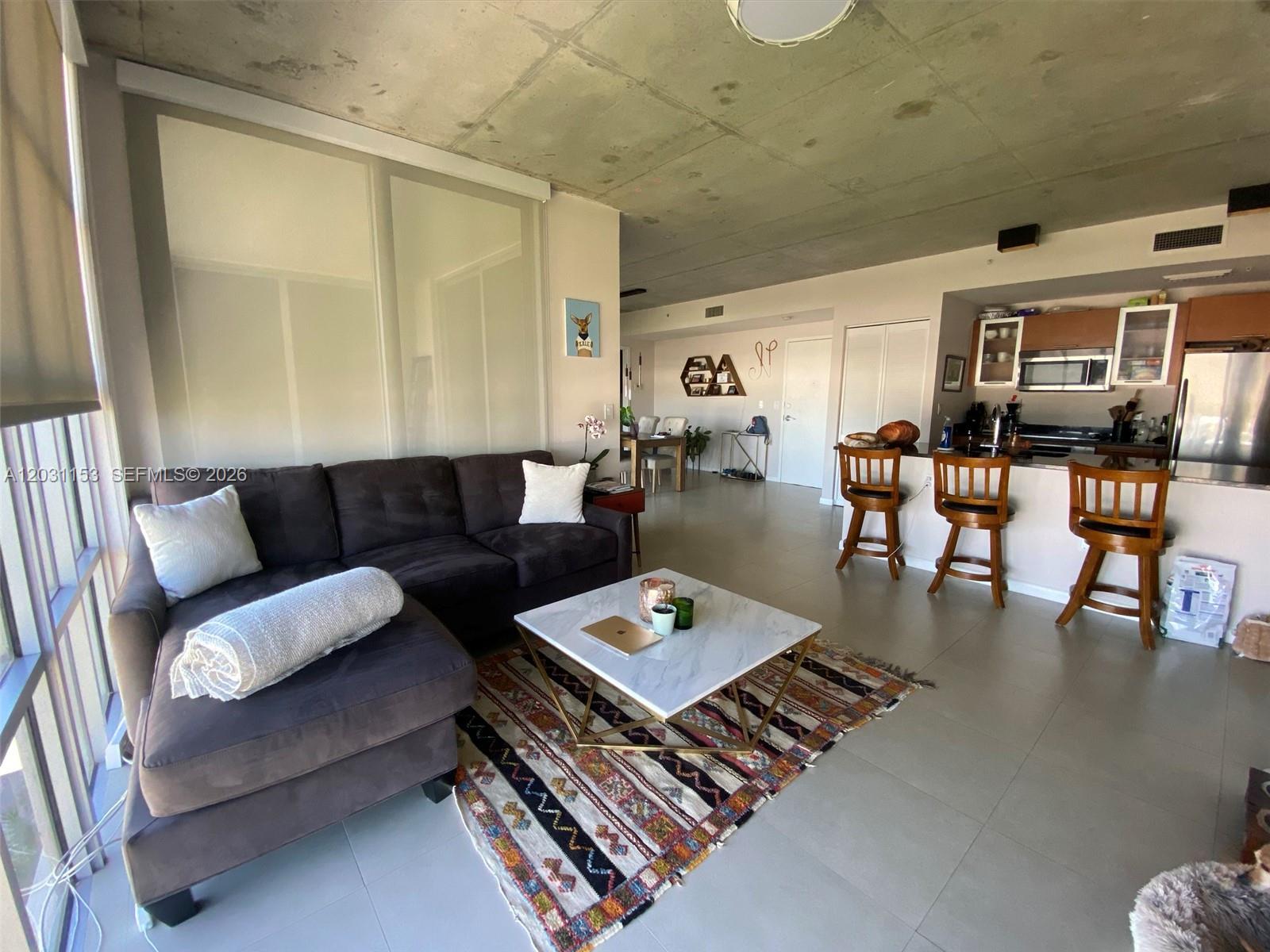 A living room with a sectional sofa, coffee table, and open kitchen with bar seating — 3451 NE 1st Ave # M0906, Miami FL 33137, MIAMI, FL