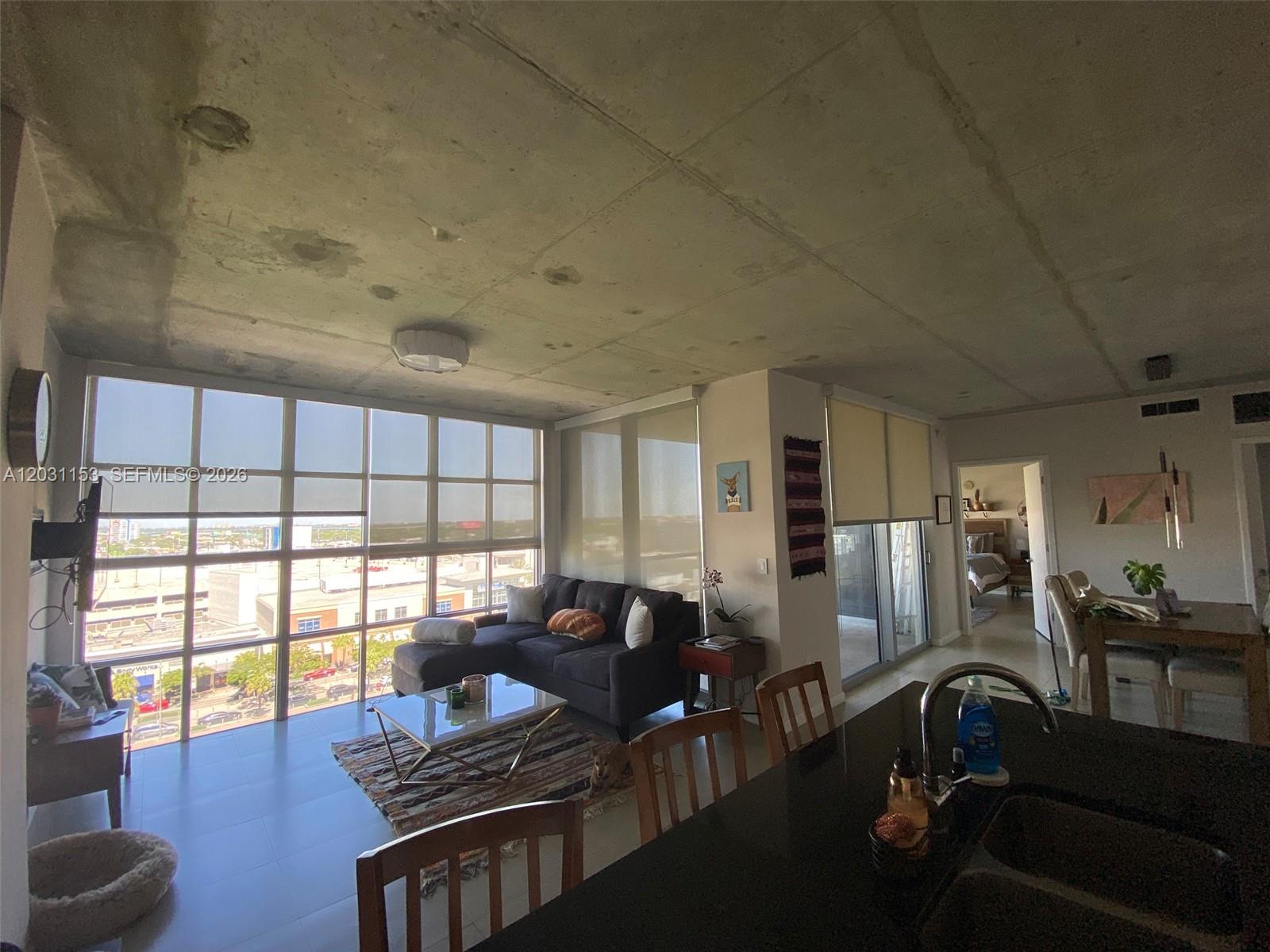 An open-concept living area features a concrete ceiling, floor-to-ceiling windows, and a kitchen island — 3451 NE 1st Ave # M0906, Miami FL 33137, MIAMI, FL