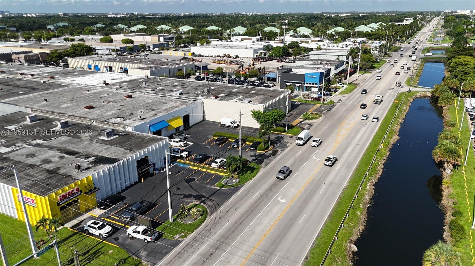 An aerial view shows a commercial building with a parking lot next to a road — 8420 NW 58th St, Doral FL 33166, DORAL, FL