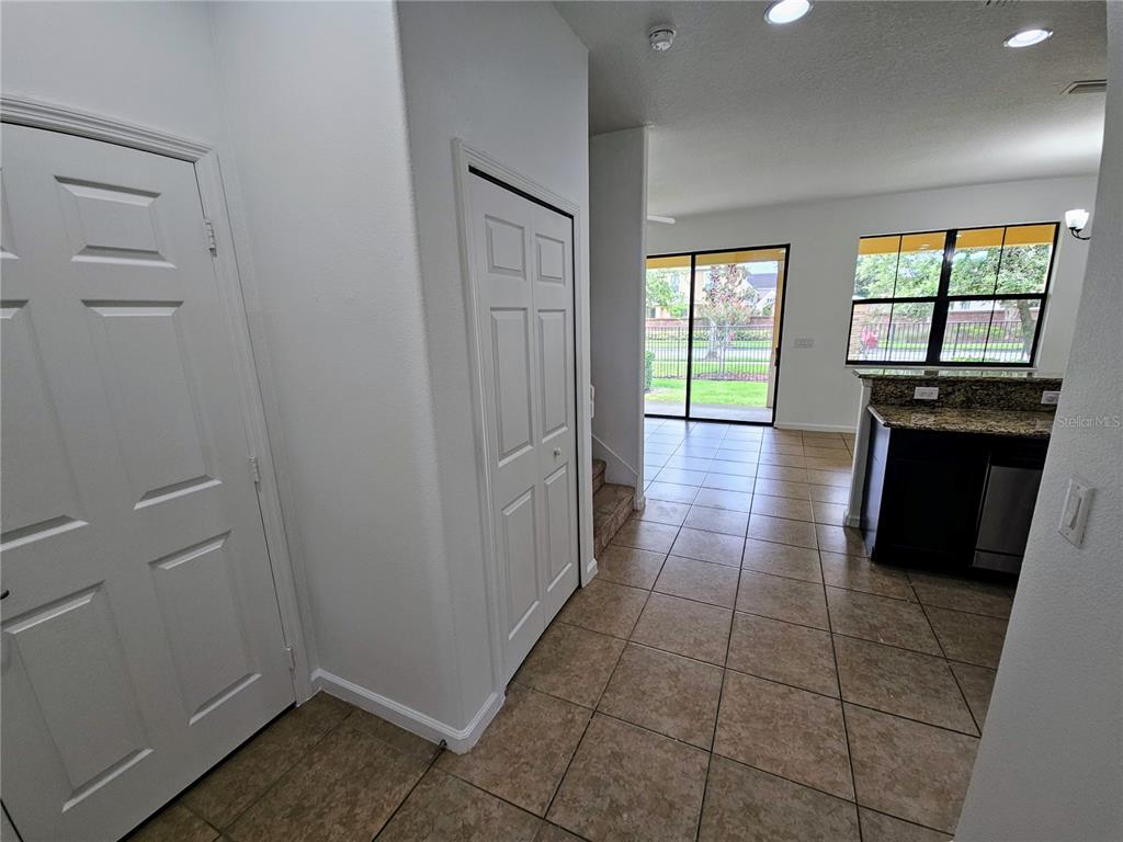 A tiled entryway leads to a kitchen with granite countertops and a sliding glass door — 1899 PORTOFINO MEADOWS BOULEVARD, ORLANDO, FL