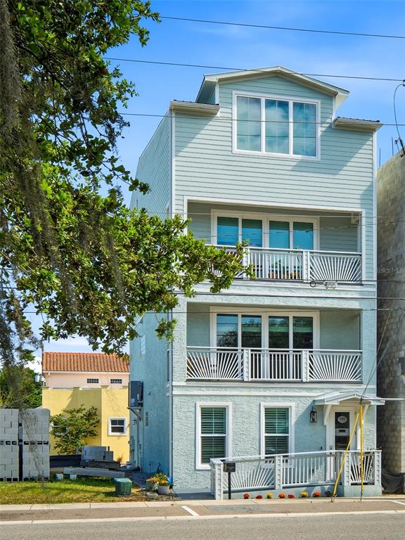 A three-story light blue house with two balconies and a ground-level entrance ramp — 140 JULIA STREET, NEW SMYRNA BEACH, FL