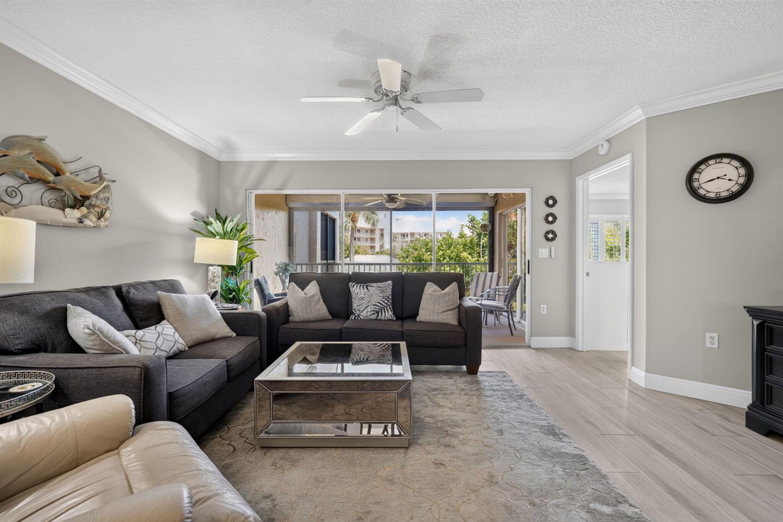 A living room features dark gray sofas, a mirrored coffee table, and a sliding glass door — 275 Palm Avenue # D, Jupiter FL 33477, JUPITER, FL