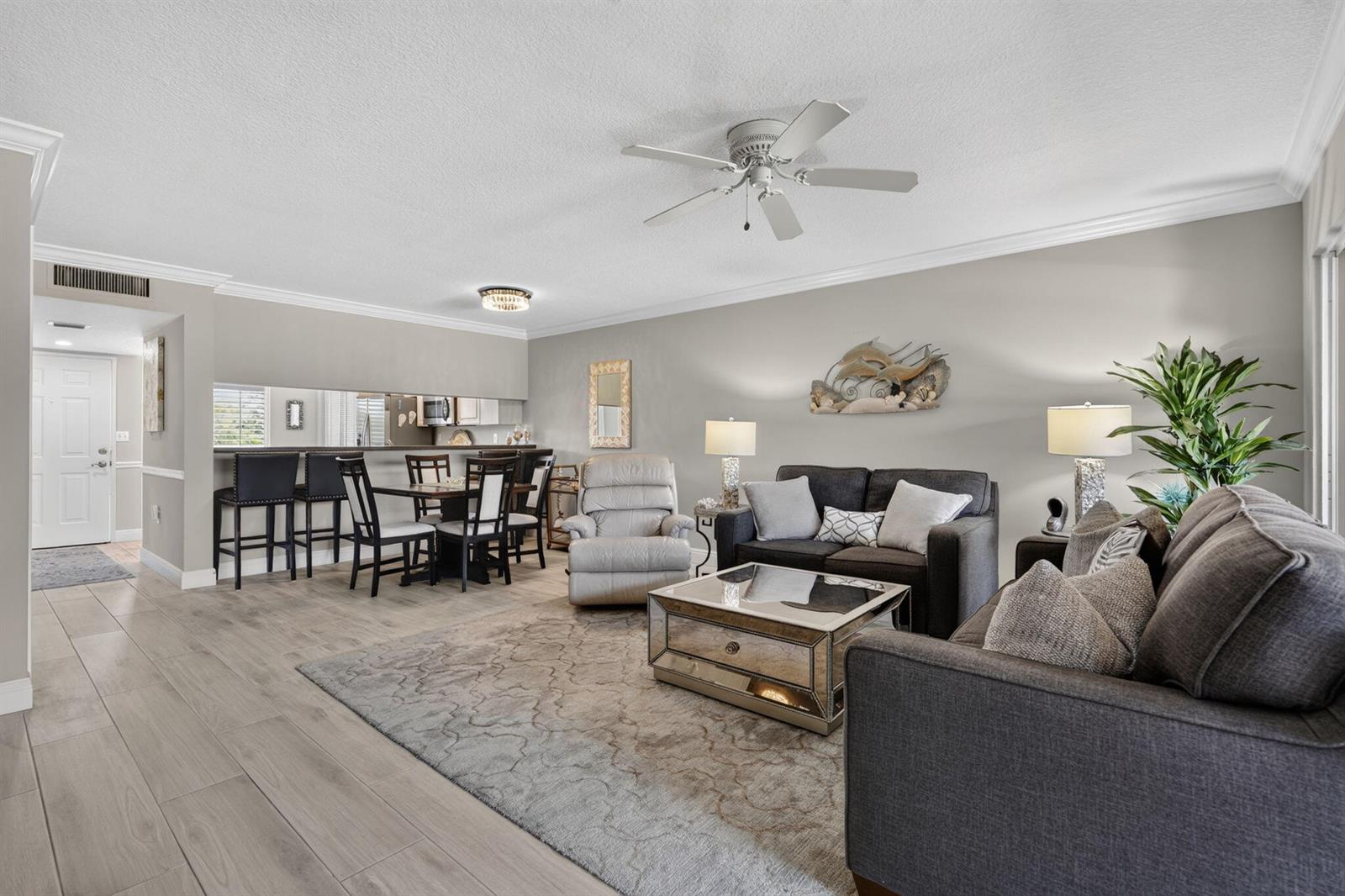 A living room with gray sofas, a mirrored coffee table, and an adjacent dining area — 275 Palm Avenue # D, Jupiter FL 33477, JUPITER, FL