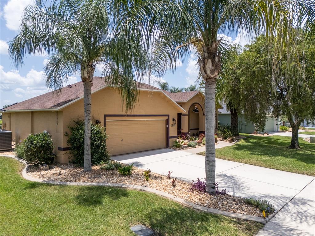 A tan single-story house with a two-car garage and palm trees in the front yard — 1887 CREEKWATER BOULEVARD, PORT ORANGE, FL