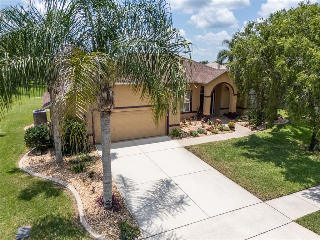 An exterior view of a tan, single-story house with a concrete driveway and palm trees — 1887 CREEKWATER BOULEVARD, PORT ORANGE, FL