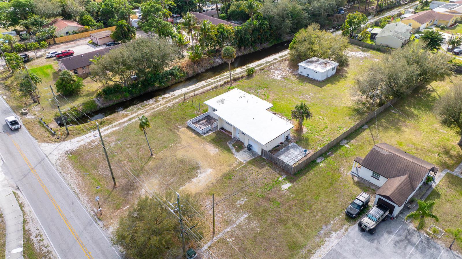 An aerial view shows a residential property with a white house, detached garage, and canal — 4475 Kirk Road, Lake Worth FL 33461, LAKE WORTH, FL
