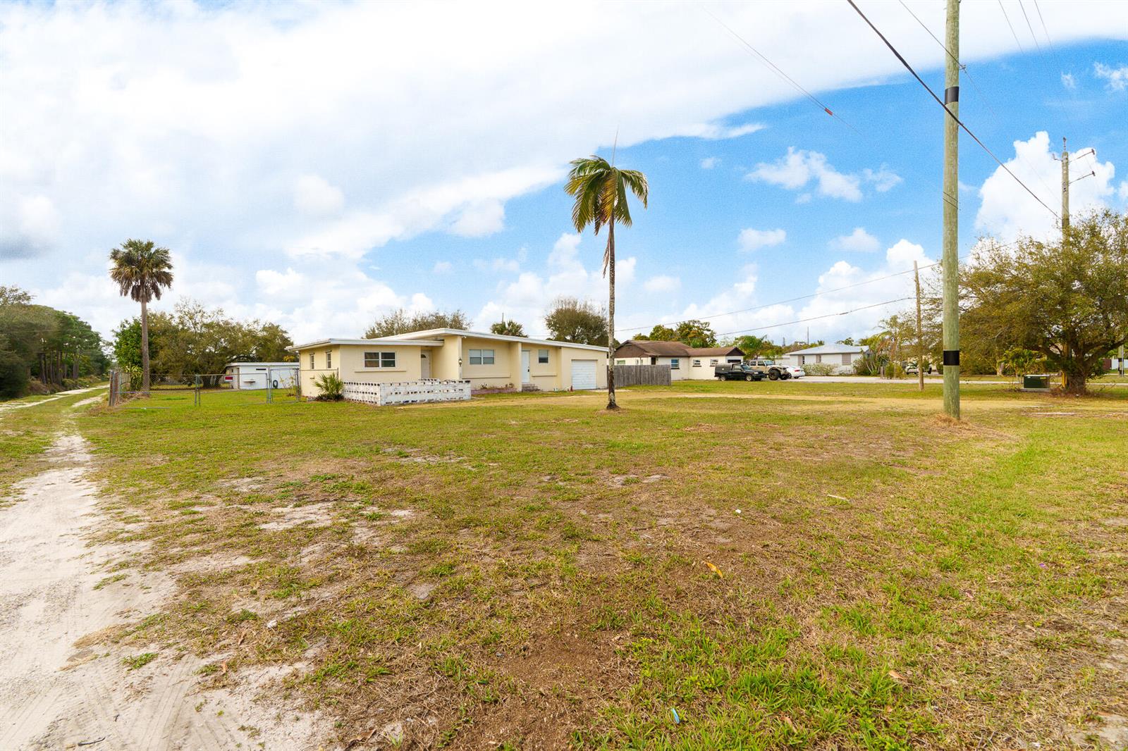 A single-story yellow house sits on a large, grassy lot with palm trees — 4475 Kirk Road, Lake Worth FL 33461, LAKE WORTH, FL