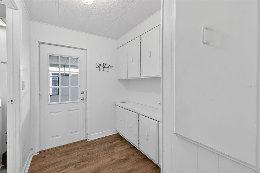 A laundry room features white cabinets, a countertop, wood-look flooring, and a glass-paneled exterior door — 401 LOMA LINDA, NORTH PORT, FL