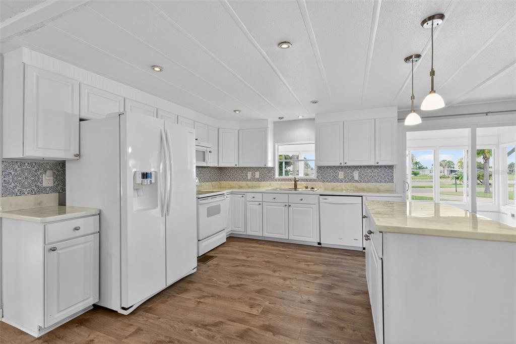 A white kitchen with wood-look flooring, stone countertops, and a large island — 401 LOMA LINDA, NORTH PORT, FL