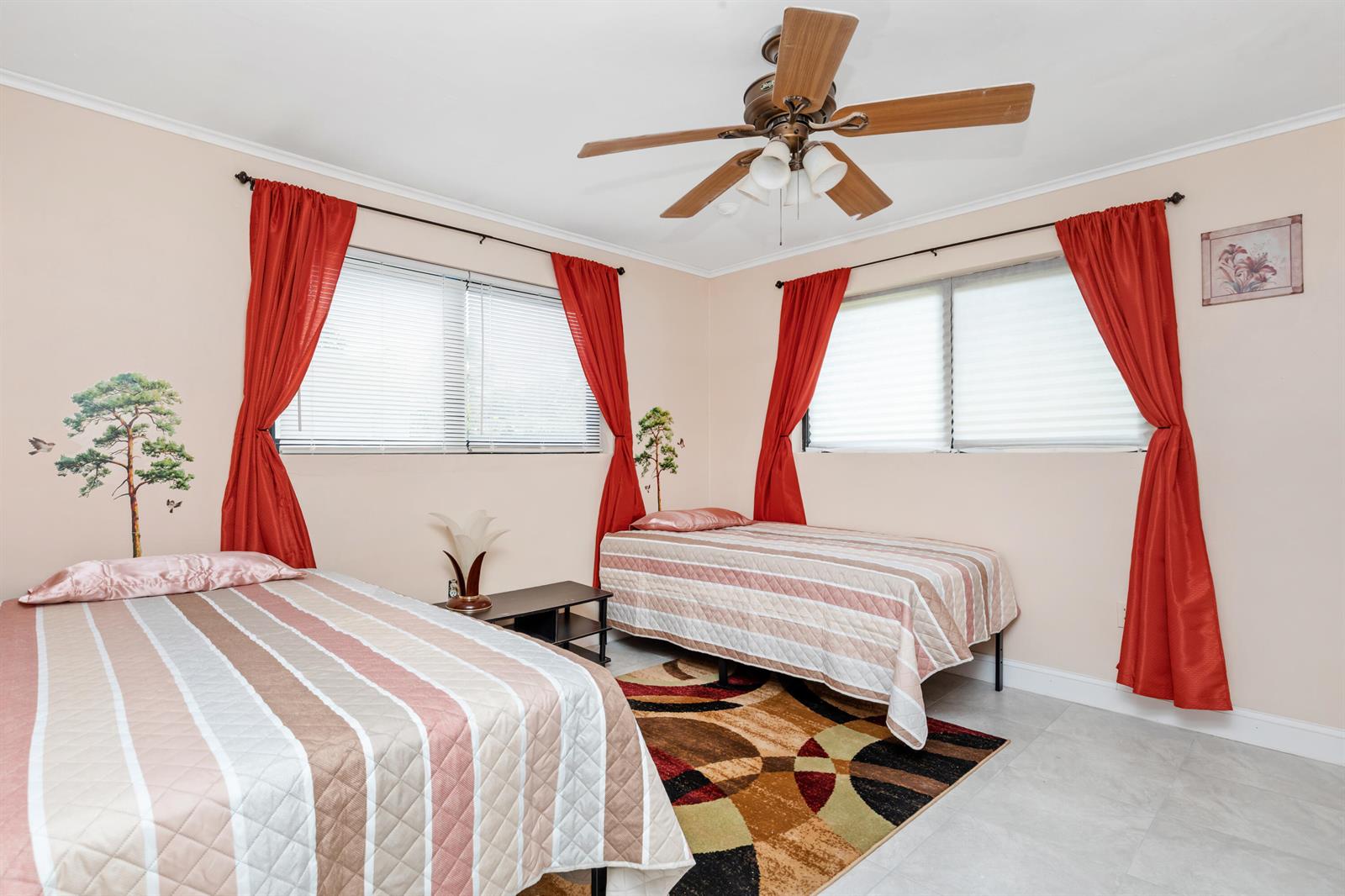 A bedroom features two twin beds, red curtains, a ceiling fan, and a patterned rug — 475 NE 113th Street, Miami FL 33161, MIAMI, FL