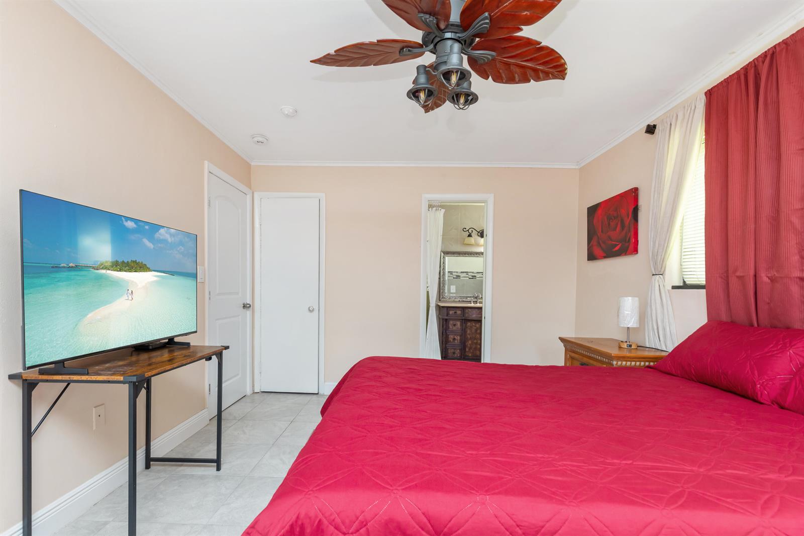 A bedroom features a red bedspread, a television on a stand, and a ceiling fan — 475 NE 113th Street, Miami FL 33161, MIAMI, FL