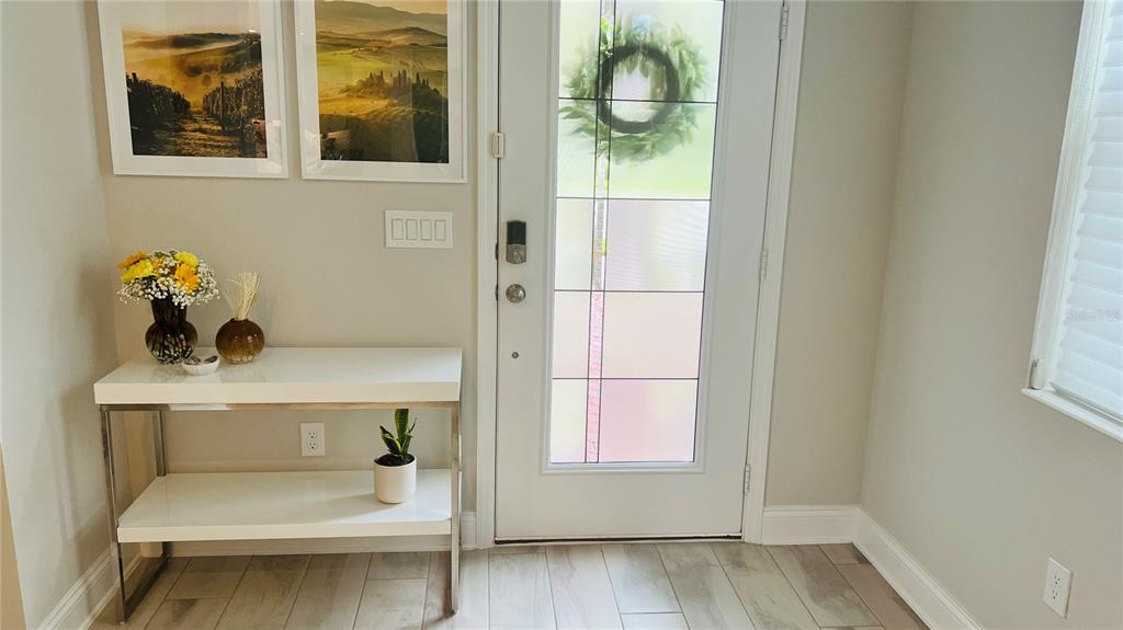 An entryway features a white console table, a glass-paneled front door, and framed wall art — 13706 WERRINGTON DRIVE, WINTER GARDEN, FL