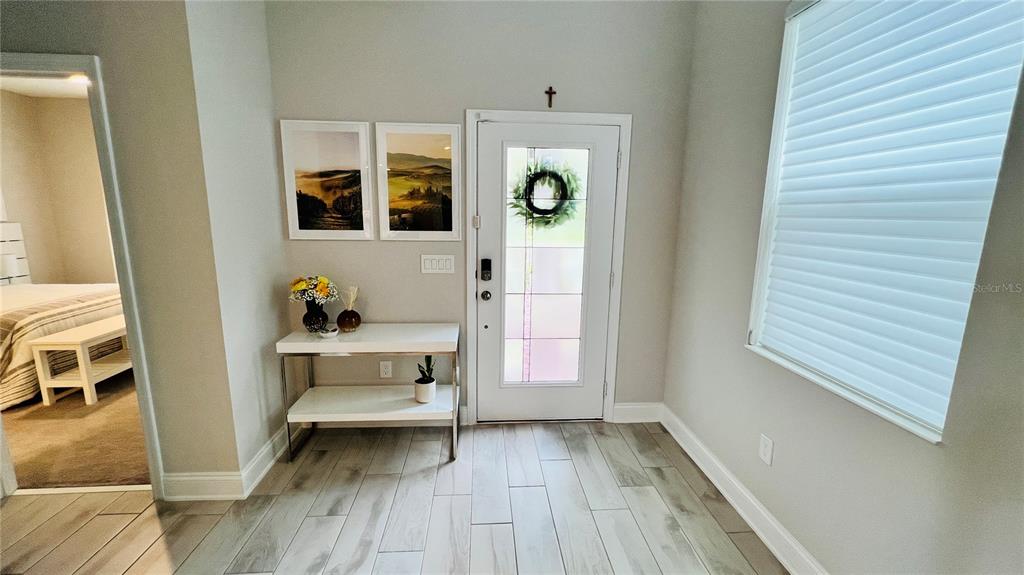 An entryway features light wood-look tile flooring, a console table, and a white front door — 13706 WERRINGTON DRIVE, WINTER GARDEN, FL