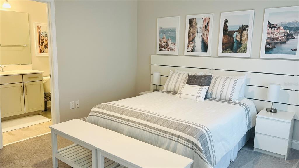 A bedroom features a bed with a white headboard, four framed prints, and an attached bathroom — 13706 WERRINGTON DRIVE, WINTER GARDEN, FL