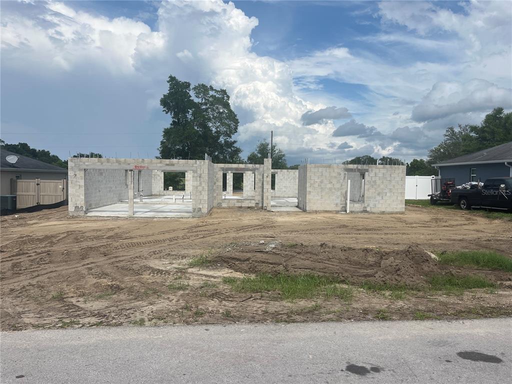 A single-story house under construction features a garage, stucco exterior, and an open drainage system — 15691 SE 97TH AVENUE, SUMMERFIELD, FL
