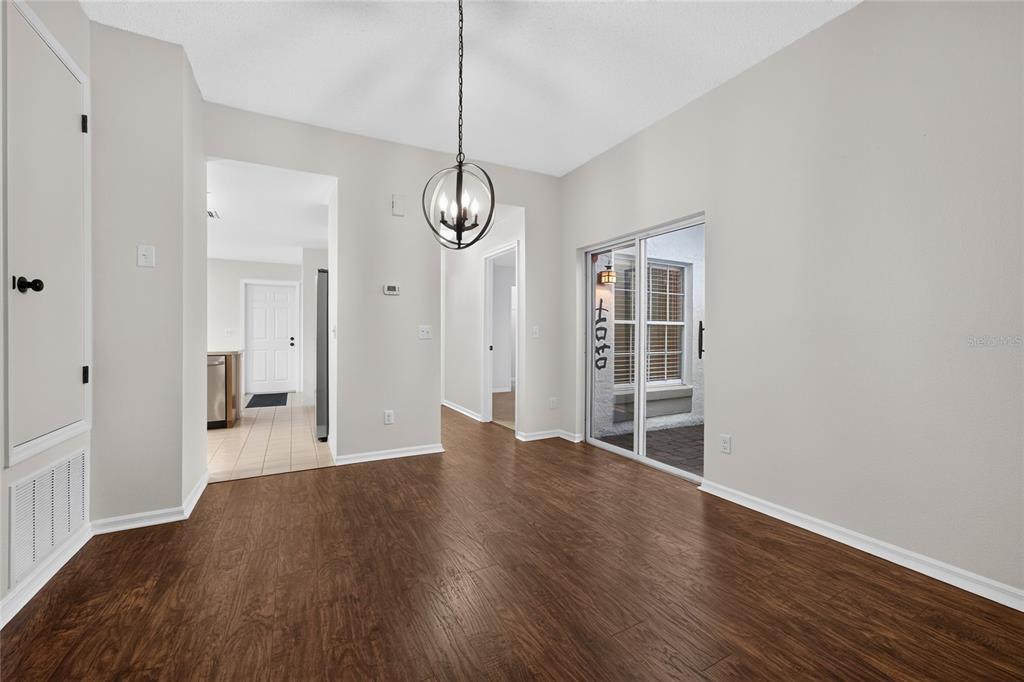 An empty dining area with wood-look flooring, a spherical chandelier, and a sliding glass door — 11206 PURPLE PLUM COURT, ORLANDO, FL