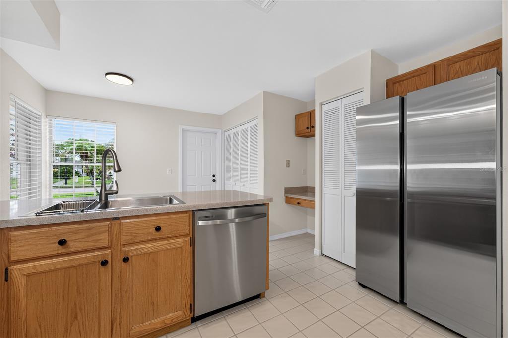 A kitchen with oak cabinets, stainless steel appliances, a sink island, and light tile flooring — 11206 PURPLE PLUM COURT, ORLANDO, FL