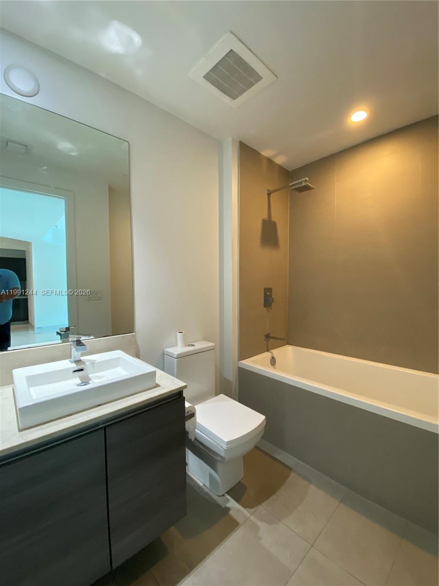 A modern bathroom features a vessel sink vanity, a toilet, and a tiled shower-tub combination — 1080 Brickell Ave # 205, Miami FL 33131, MIAMI, FL