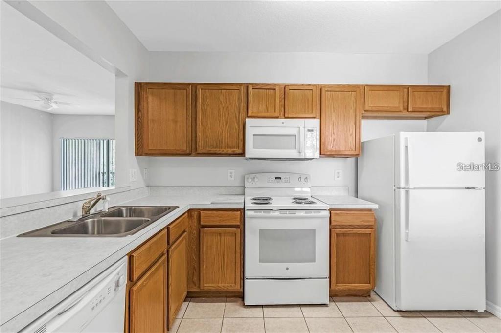 A kitchen with oak cabinets, white appliances, a double sink, and light-colored countertops — 9519 NEWDALE WAY UNIT 201, RIVERVIEW, FL