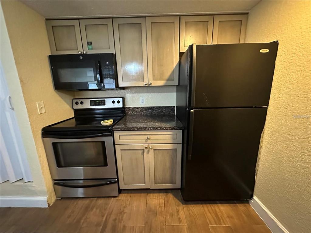 A kitchen features light wood cabinets, a black refrigerator, a stainless steel stove, and countertops — 5108 CONROY ROAD UNIT 1713, ORLANDO, FL
