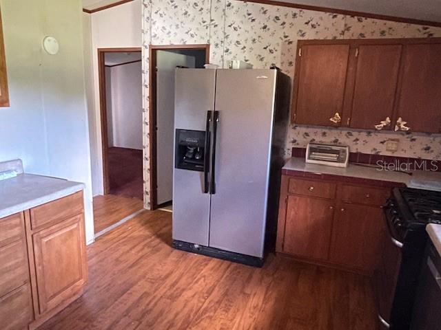 A kitchen features wood cabinets, a stainless steel refrigerator, and floral wallpaper — 7196 NW 205TH STREET, ALACHUA, FL