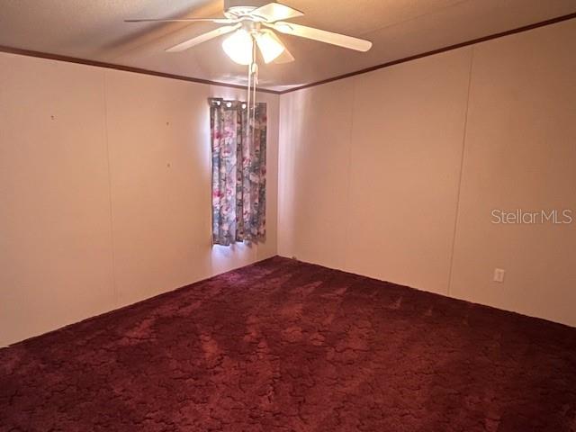 An empty bedroom features dark red carpeting, beige walls, and a ceiling fan — 7196 NW 205TH STREET, ALACHUA, FL