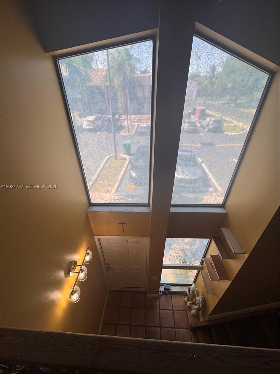 An elevated view of an entryway with large windows, tile flooring, and a wooden staircase — 6547 SW 116th Pl # C, Miami FL 33173, MIAMI, FL