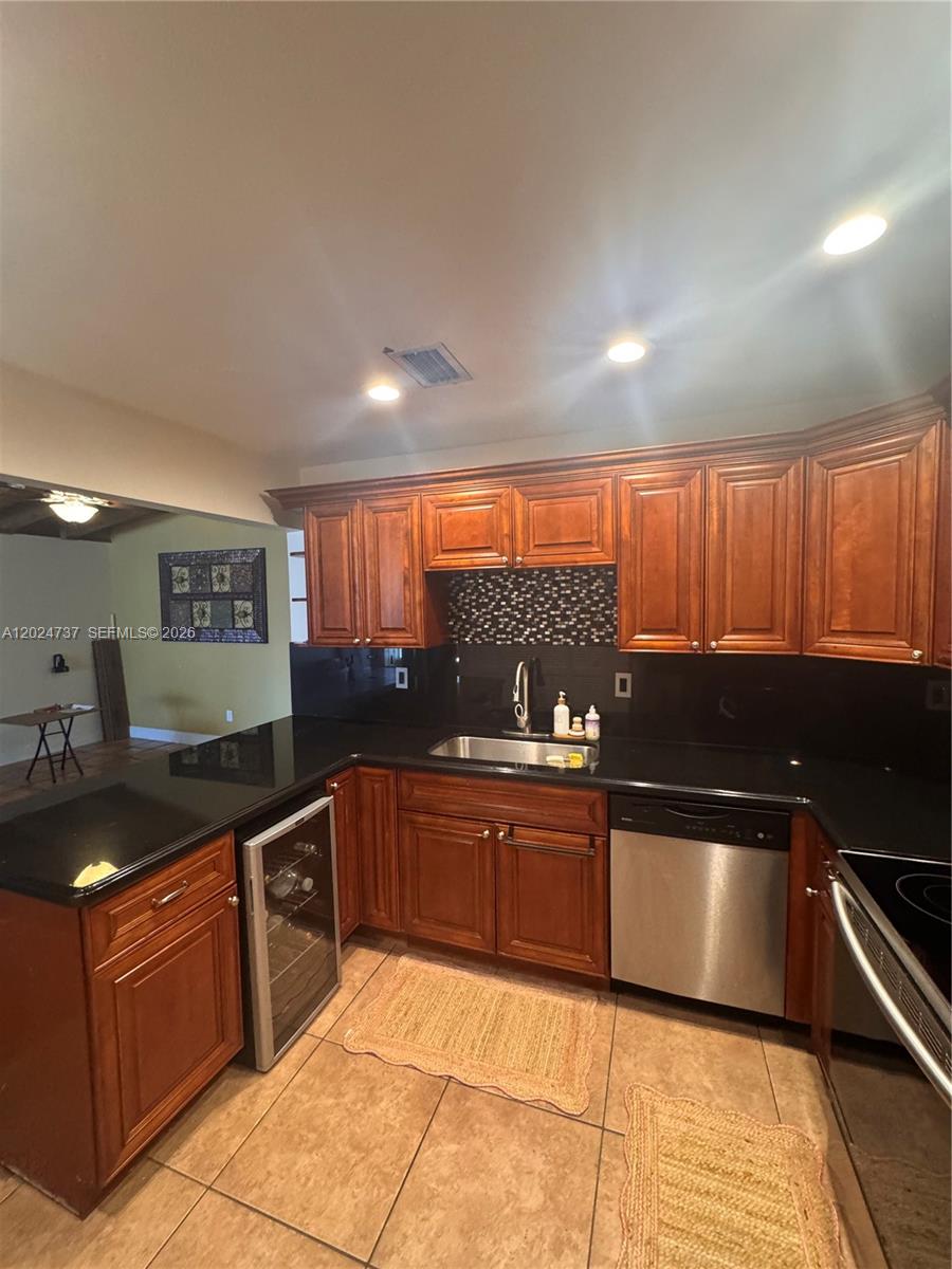 A kitchen features wood cabinets, black countertops, a stainless steel dishwasher, and tile flooring — 6547 SW 116th Pl # C, Miami FL 33173, MIAMI, FL