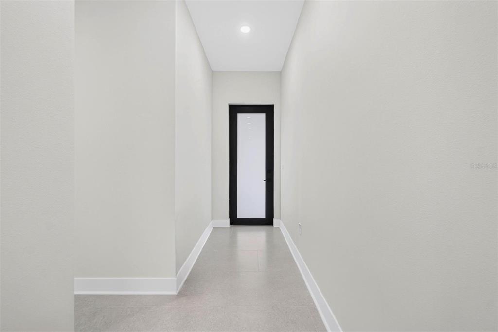 A narrow hallway with light gray walls, white baseboards, tile flooring, and a black-framed door — 2227 32ND AVENUE N, ST PETERSBURG, FL