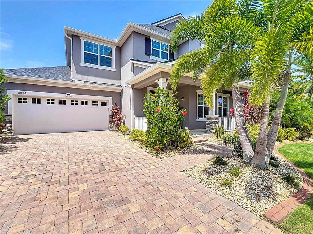 A two-story gray house features a paved driveway, a garage, and a front porch — 8054 BUSHMASTER AVENUE, ORLANDO, FL