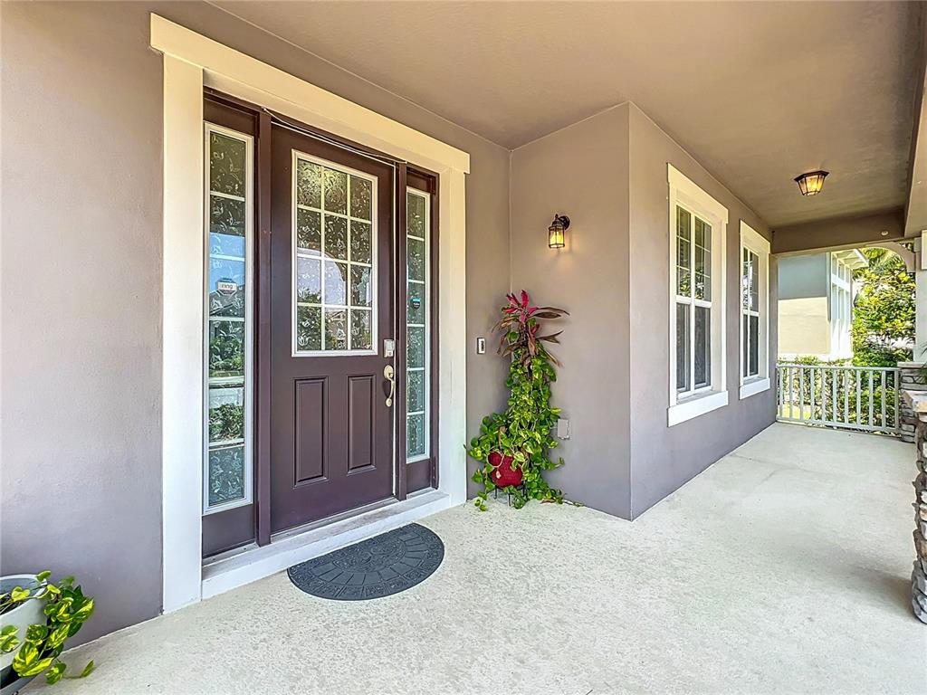A covered front porch features a dark brown door with sidelights and a concrete floor — 8054 BUSHMASTER AVENUE, ORLANDO, FL