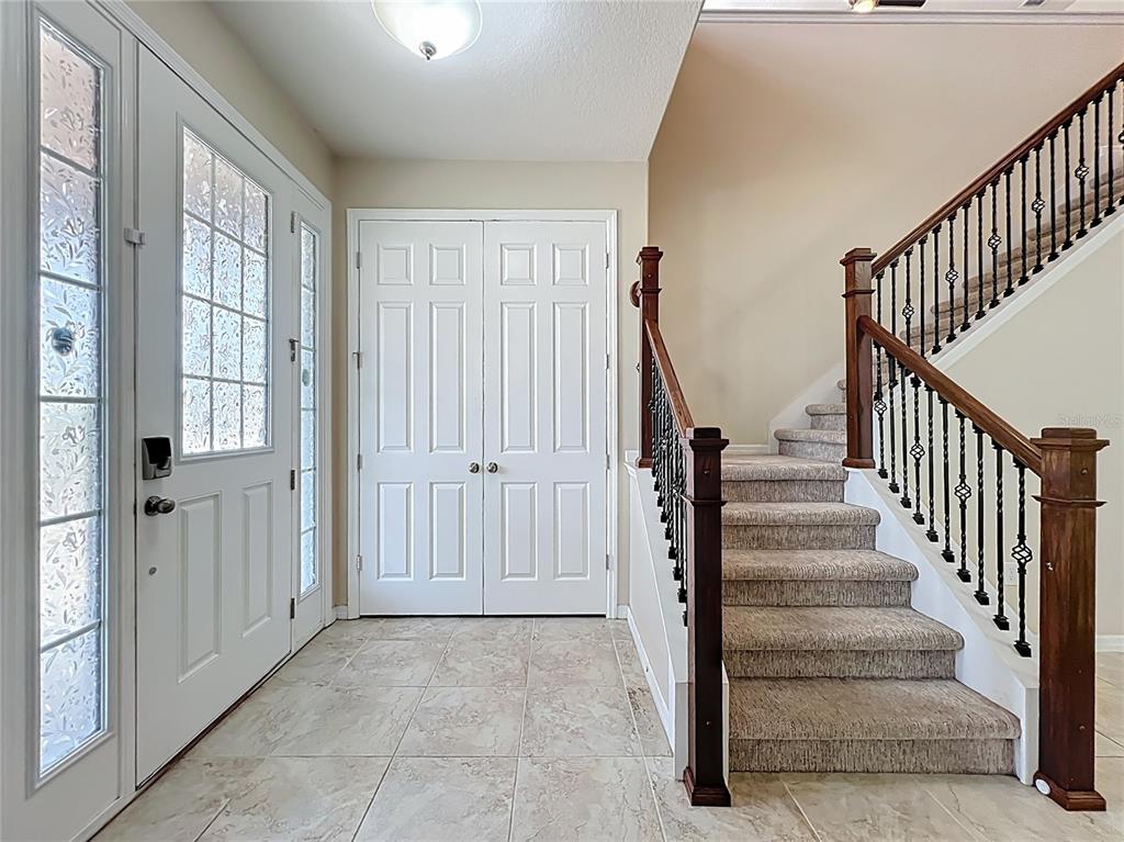 An entryway features a tiled floor, a double front door, and a carpeted staircase — 8054 BUSHMASTER AVENUE, ORLANDO, FL