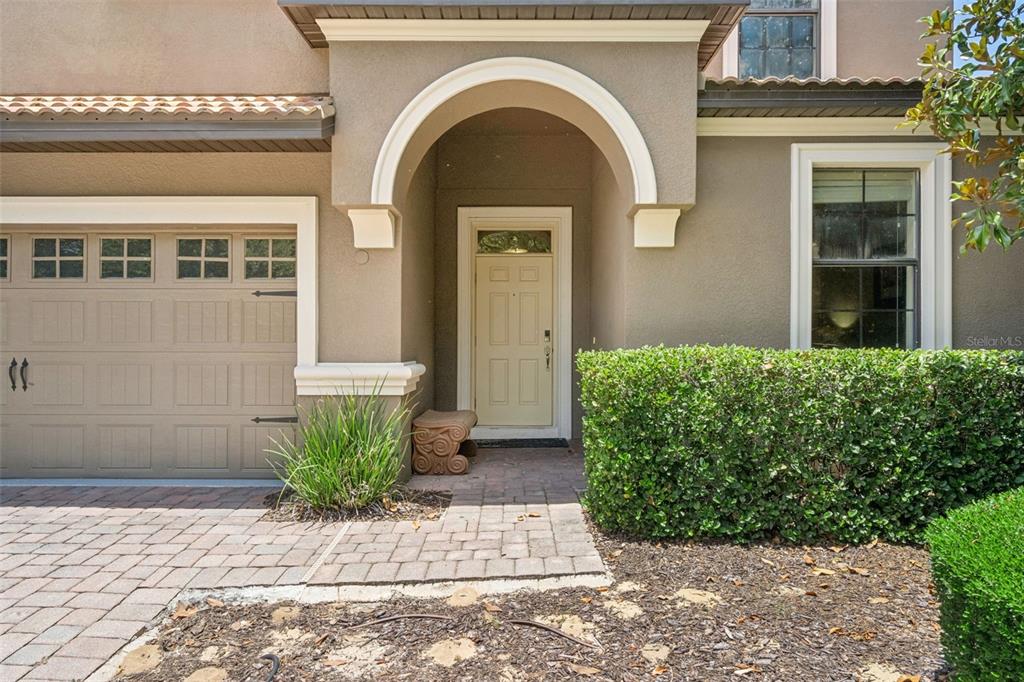 The exterior of a house features a beige garage, a front door, and a landscaped hedge — 1420 MOON VALLEY, DAVENPORT, FL