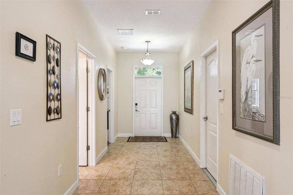 A tiled entryway features a white front door, light walls, and decorative wall art — 1420 MOON VALLEY, DAVENPORT, FL