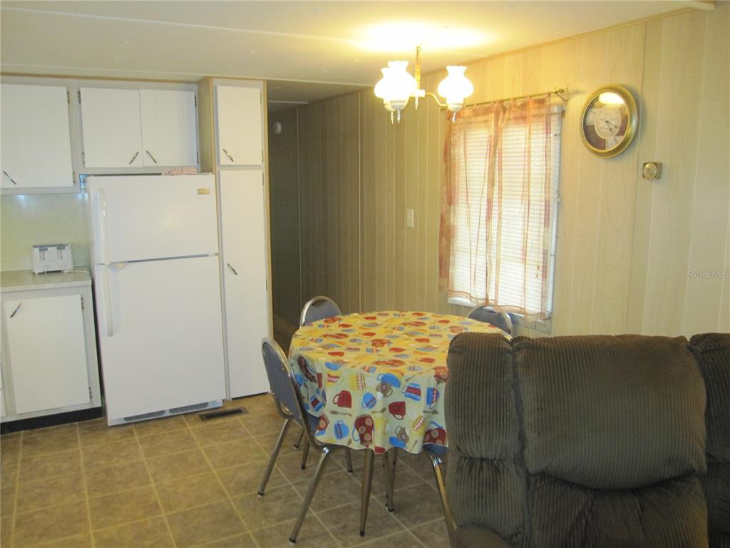 A kitchen and dining area featuring a round table, white appliances, and wood-paneled walls — 39015 HILLCREST DRIVE, ZEPHYRHILLS, FL