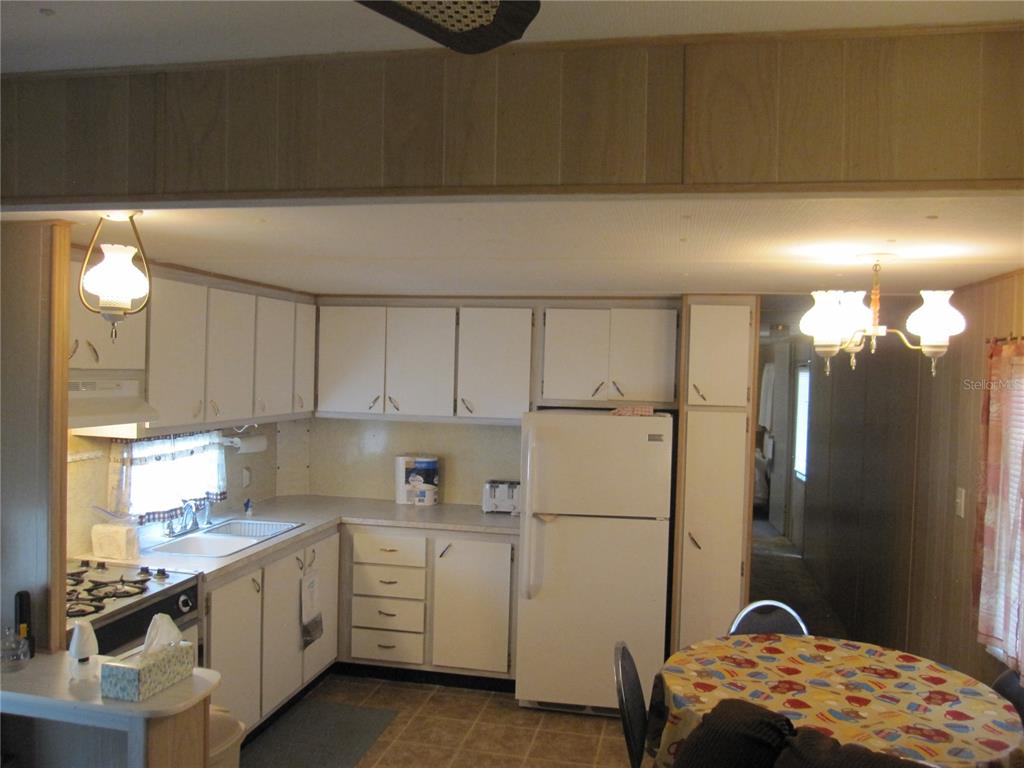 A kitchen with white cabinets, a white refrigerator, and a small dining table — 39015 HILLCREST DRIVE, ZEPHYRHILLS, FL
