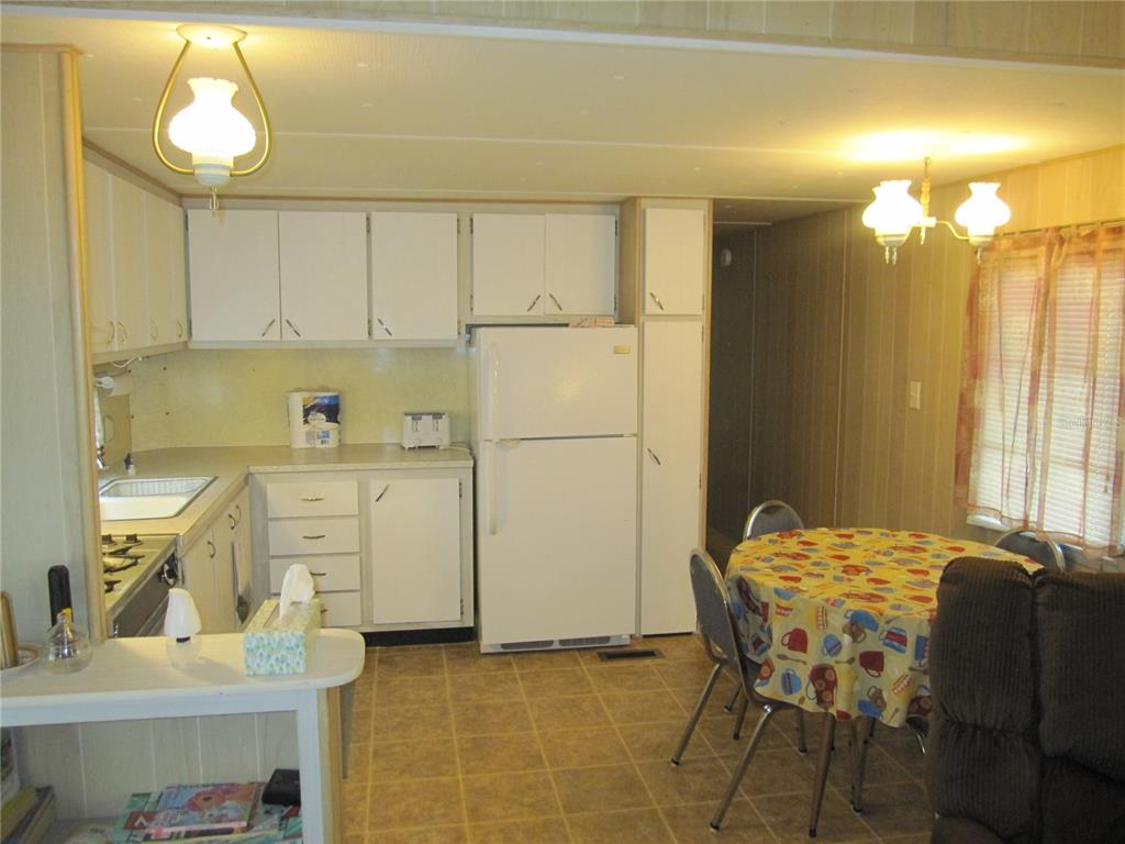 A kitchen with white cabinets, a white refrigerator, and a small dining table with chairs — 39015 HILLCREST DRIVE, ZEPHYRHILLS, FL