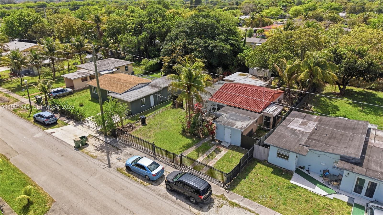 An aerial view shows two residential houses with fenced yards and parked cars on the street — 60 NW 128th St, North Miami FL 33168, NORTH MIAMI, FL