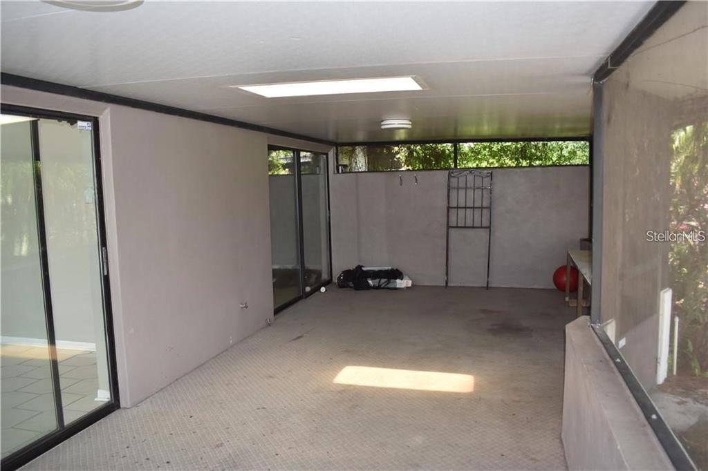 A covered outdoor patio features a concrete floor, sliding glass doors, and a screen enclosure — 11301 DAREWOOD PLACE, TAMPA, FL