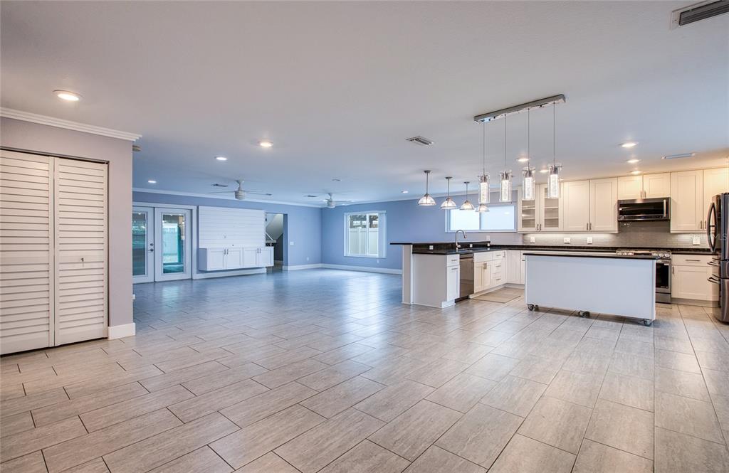 A spacious open-concept kitchen and living area with light tile flooring and white cabinetry — 6408 7TH AVENUE N, ST PETERSBURG, FL