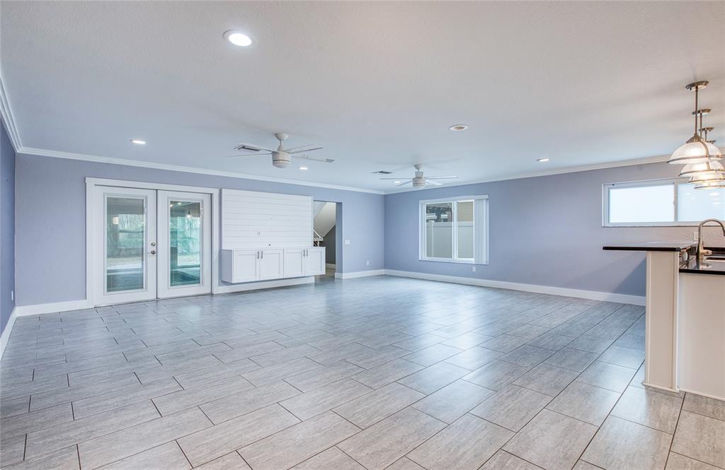 A spacious room with light blue walls, gray tile flooring, ceiling fans, and glass doors — 6408 7TH AVENUE N, ST PETERSBURG, FL