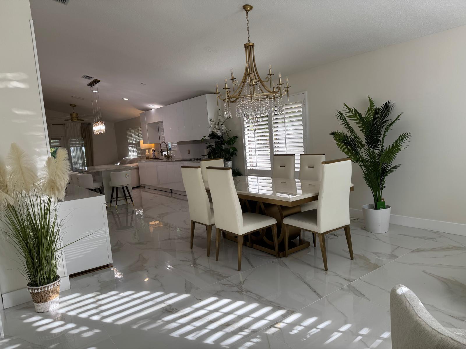 A dining area with a chandelier, white chairs, and a table on marble-look tile flooring — 544 NW 38th Avenue, Deerfield Beach FL 33442, DEERFIELD BEACH, FL