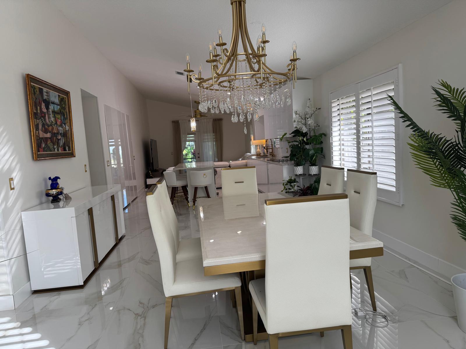 A dining room features a marble table, white upholstered chairs, and a large crystal chandelier — 544 NW 38th Avenue, Deerfield Beach FL 33442, DEERFIELD BEACH, FL