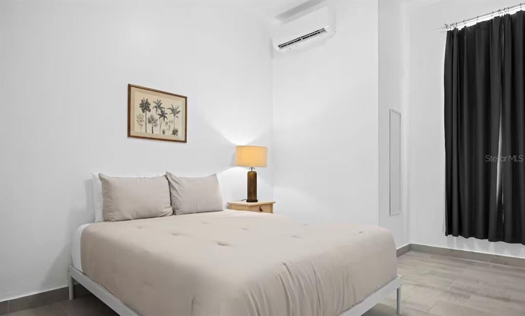 A bedroom features a bed with a beige comforter, a nightstand, and dark curtains — 250 CALLE DEL PARQUE UNIT 2A, SAN JUAN, PR