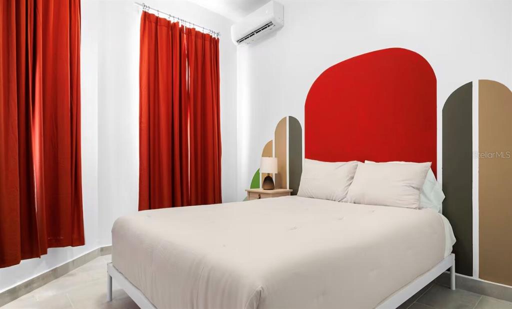 A bedroom features a bed with a beige comforter, red curtains, and painted wall arches — 250 CALLE DEL PARQUE UNIT 2A, SAN JUAN, PR