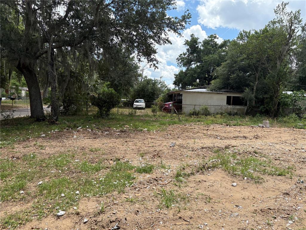 A vacant, sandy lot with scattered debris sits in front of trees and a small building — 510 BRIAR MEADOWS DR, VALRICO, FL