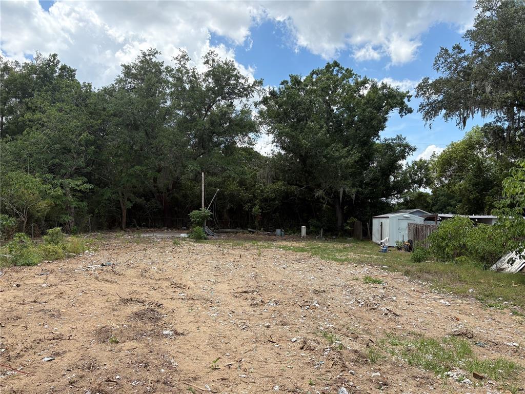 A cleared, sandy residential lot features a small shed and mature trees in the background — 510 BRIAR MEADOWS DR, VALRICO, FL