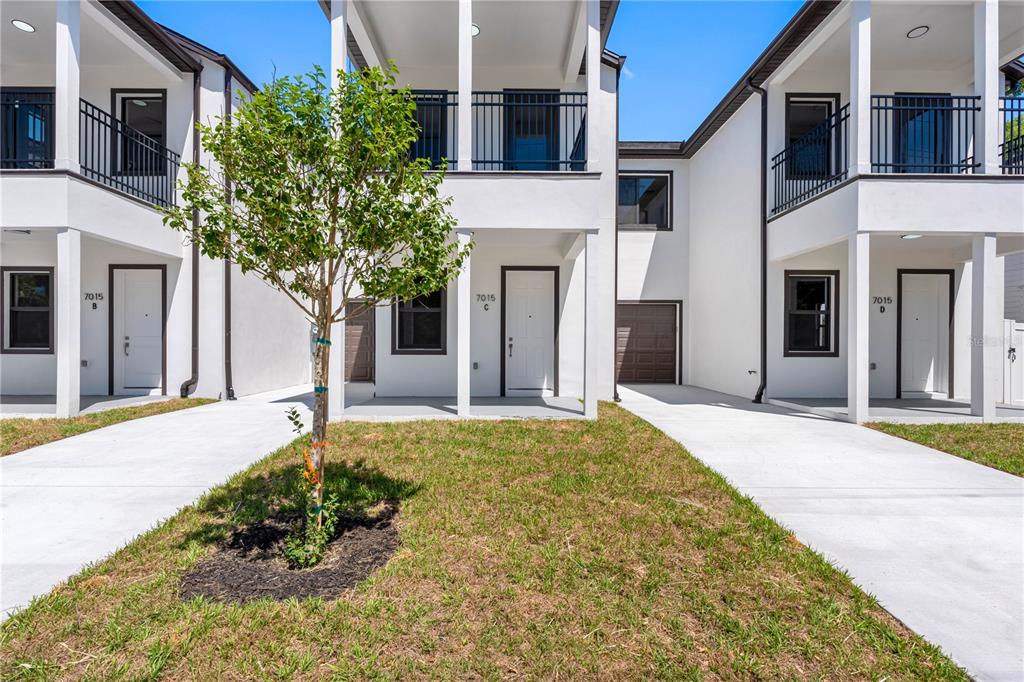 A row of modern white townhouses with concrete driveways and a small tree in front — 7015 N CENTRAL AVENUE Unit C, TAMPA, FL