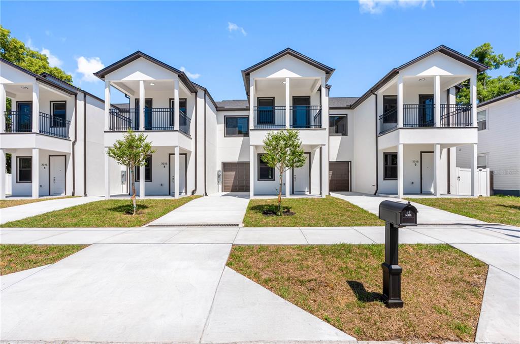 A row of modern white townhouses with balconies, garages, and concrete driveways under a blue sky — 7015 N CENTRAL AVENUE Unit C, TAMPA, FL
