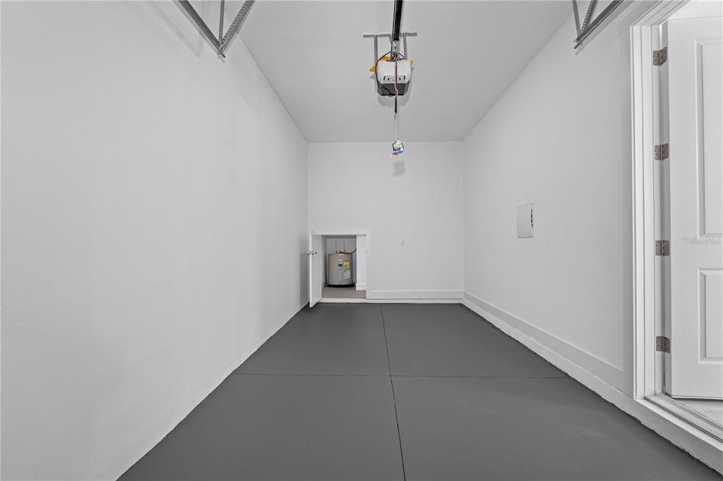 A garage with a gray floor, white walls, and an open water heater closet — 7015 N CENTRAL AVENUE Unit C, TAMPA, FL
